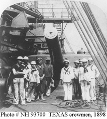 Crewmen pose in front of the battleship's port side (forward) 12&quot;/35 gun, 1898. This view looks aft, with boat stowage and a winch at the left. Original photograph was printed on a stereograph card by Strohmeyer &amp; Wyman, New York, 1898.